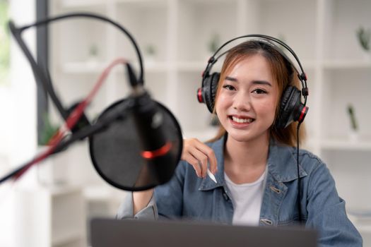 Young asian woman makes a podcast audio recording at home.
