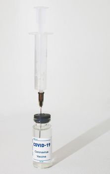 Syringe stuck in an ampoule on a white background.