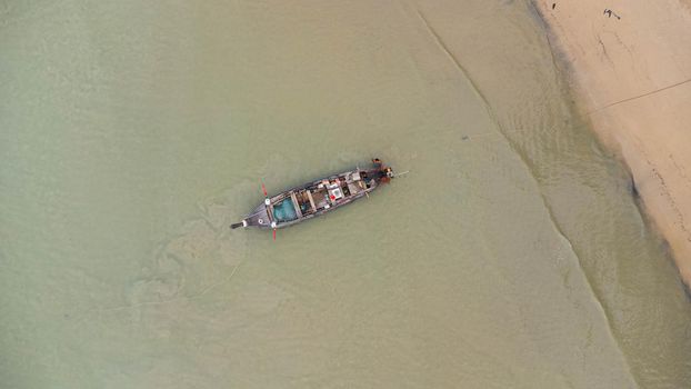 Aerial view from drones of fishing boats in the shore during low tide. Top view of Thai traditional longtail fishing boats in the tropical sea.