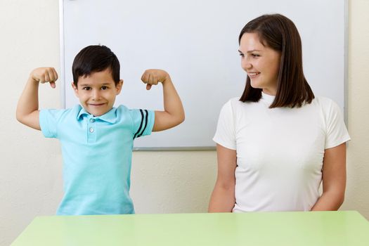 Boy is showing his arm muscles to his teacher