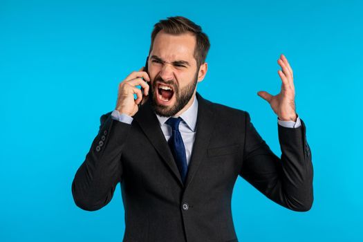 Businessman screaming on mobile phone. Having nervous breakdown at work