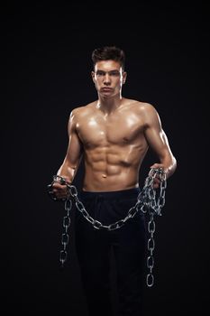 Teenager men sportsmen. Portrait of a brutal boy with chains. Athlete bodybuilder on black background.
