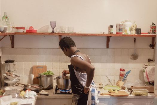 black ivorian african young fit woman cooking at home in small kitchen in summertime