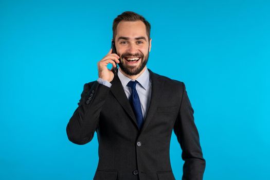 Businessman have conversation using mobile phone isolated on blue background. Business guy in formal suit gladly talks with colleague. Office employee, wage worker, weekdays concept