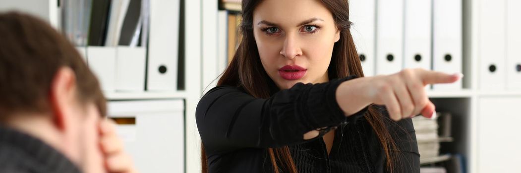 Aggressive female boss points hand to exit, dismissing sad employee