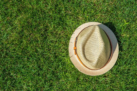Straw hat on the green grass background with copy space