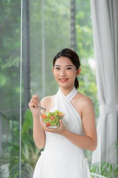 Portrait of happy young woman eating vegetables salad