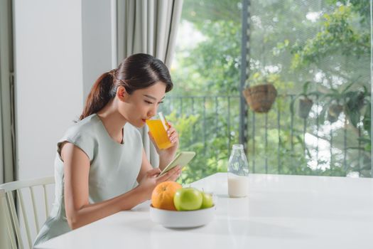 The girl has a healthy breakfast on stylish cozy home at the morning while checking her email on mobile.