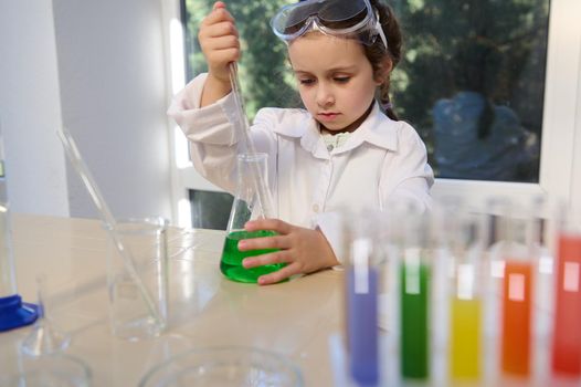 Little European girl making scientific experiments, inspired by learning Chemistry. Science, chemical education concept