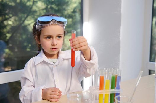 Inquisitive preschooler watches the chemical reaction taking place in test tube during scientific experiment. Chemistry