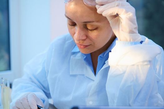 Close-up portrait of a confident multi-ethnic woman scientist, medical biologist in white lab coat in science laboratory