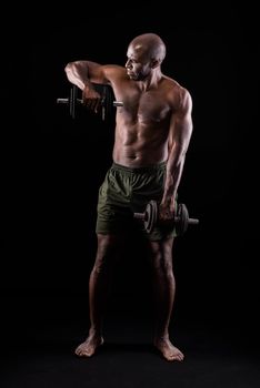 Front view of a muscular man standing doing triceps exercise with dumbbells on a black background