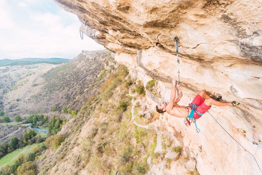 Aerial view of a rock climber hanging on with his two hands in a rock formation