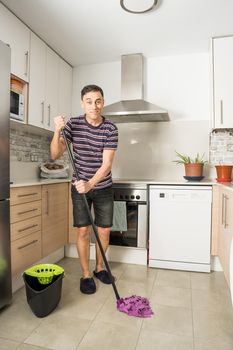 Smiling man mopping the kitchen floor. Household chores concept.