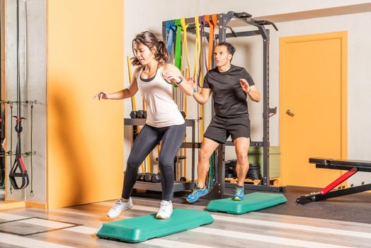 Athlete woman and man doing lateral step up jumps in health club