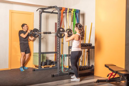 Man and woman putting weight plate on bar in gym