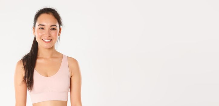 Sport, wellbeing and active lifestyle concept. Close-up of smiling attractive asian fitness girl, female gym client or sportswoman in sports bra looking ready for workout, start training.
