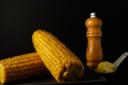 corn on the cob with pepper pot and butter on a spoon