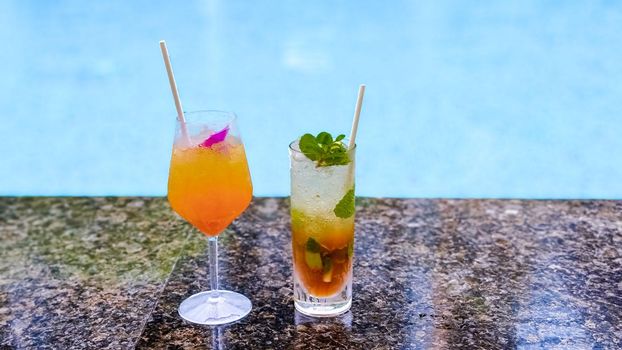Orange cocktail and mojito at a swimming pool on a luxury vacation