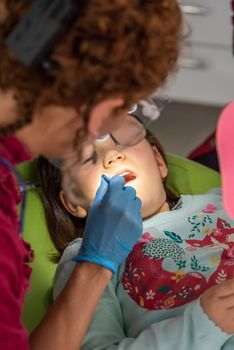 Dentist examining young girl in dental clinic