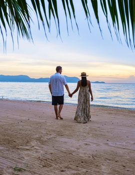 Men and women walking on the beach in Pattaya during sunset in Thailand Ban Amphur beach. couple walking on a tropical beach with palm tree and hammock during sunset