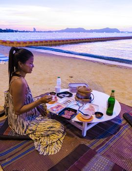 women bbq cooking noodle soup on the beach in Pattaya during sunset in Thailand Ban Amphur beach
