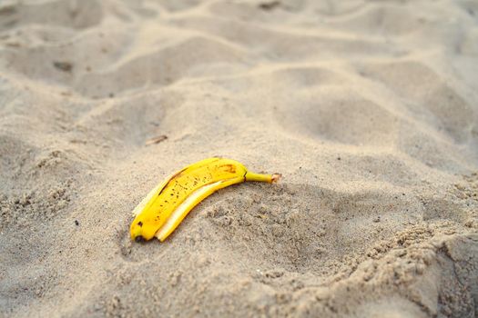 banana peel lying on the sand beach. beach pollution