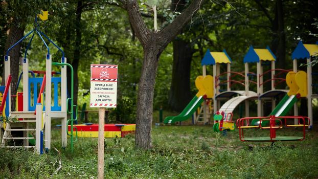 Horenka, Ukraine - August 25, 2022: The consequences of russian invasion in Kyiv region near Gostomel. Playground and sign. Words on the sign: Beware Mines
