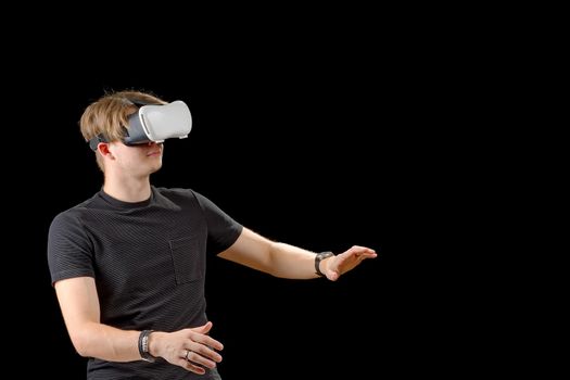 Young man wearing virtual reality VR glasses, goggles isolated on black background. Inside A Metaverse