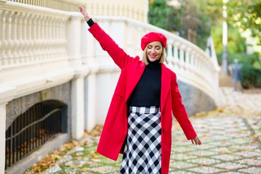 Cheerful woman in stylish wear walking near fence