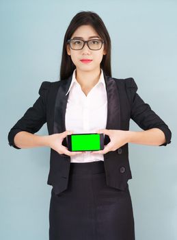 Young women in suit holding her  smartphone mock up green screen standing against blue background