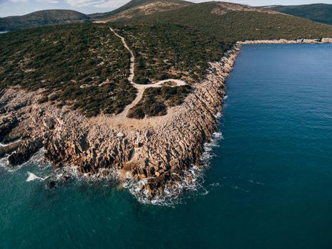 Rocky coast of the Lustica peninsula in Montenegro. Aerial drone view. Foamy waves hit the coast.