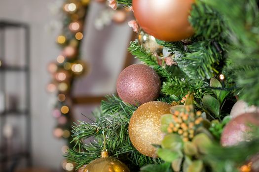 Christmas holiday decorations with lights and garland.Decorated Christmas tree with sparkling pink and golden baubles,lights, pink bow and glitter balls