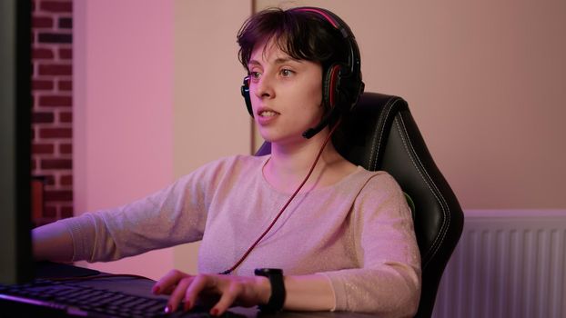 Closeup of woman with gaming headset playing multiplayer first person shooter streaming gameplay
