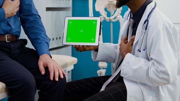 Specialist showing horizontal greenscreen on tablet to senior patient