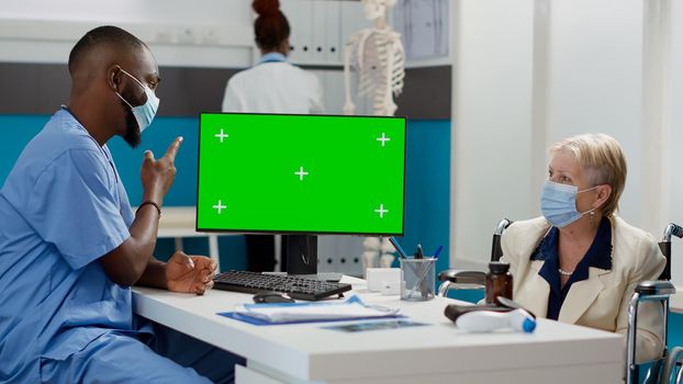 Man and patient with impairment using computer with greenscreen