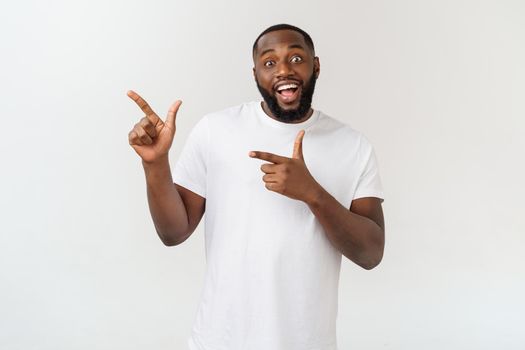 Young amazed African American pointing his finger at white background with copy space for your advertisement