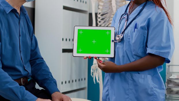 Specialist holding horizontal greenscreen on tablet at checkup