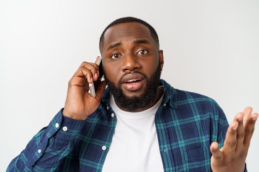 A young African American man talking on his cellular phone with a concerned or serious look on his face