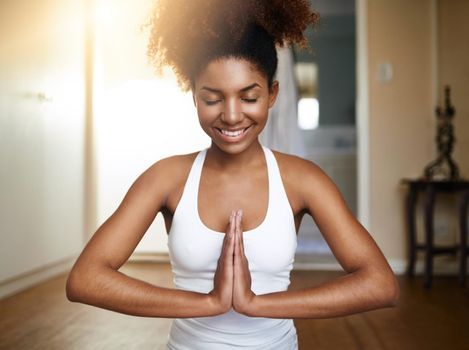 Happiness and harmony. a sporty young woman practicing yoga indoors.