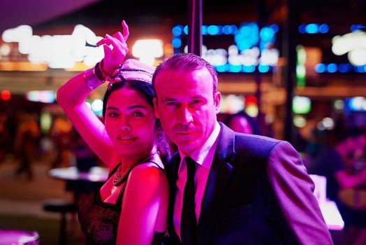 Hes a shady man in a seedy place. Portrait of a seedy businessman standing with a bar girl in a go go bar in Thailand.