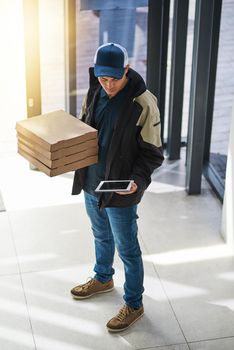 Double-checking if hes at the right location. a young man making a pizza delivery in an office.