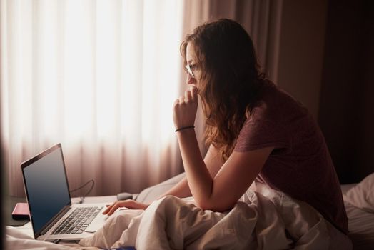 Rise and shine and get online. a young woman using a laptop while sitting in bed.