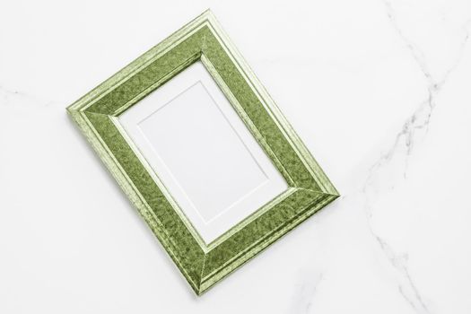 Green photo frame on marble, flatlay