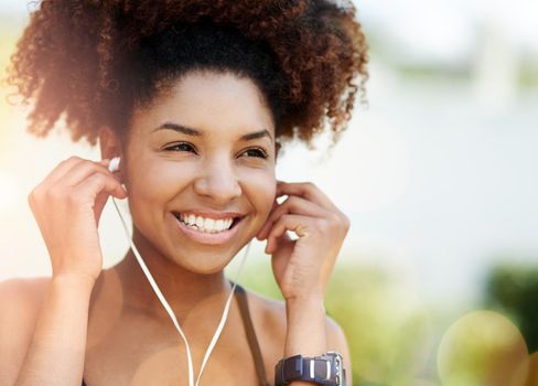 Music is my inspiration. a young woman inserting her earphones before a run.