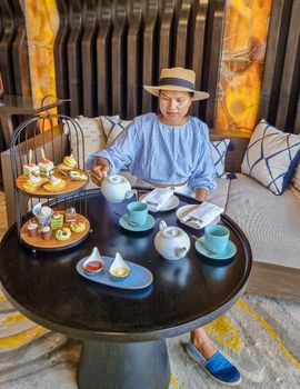 Asian women having a Luxury high tea with snack and tea in a luxury hotel