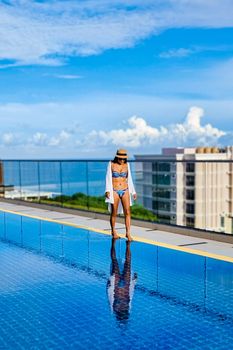 Asia women with a hat at a rooftop swimming pool at a luxury hotel