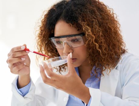 She just needs a single drop. a young female scientist analysing a sample in the lab.