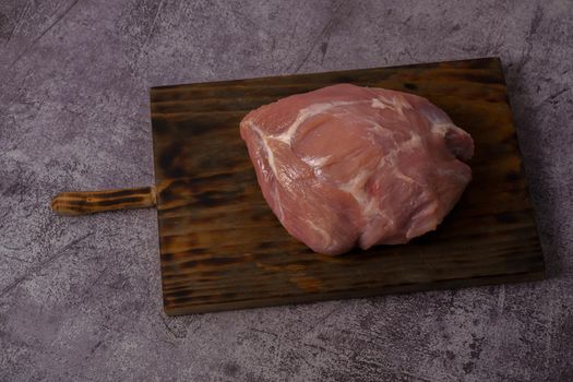 piece of raw pork tenderloin on wooden board