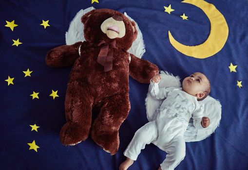 Alright Teddy, its up to us to protect the world. Concept shot of an adorable baby boy and a teddy bear wearing angel wings against an imaginary night time background.